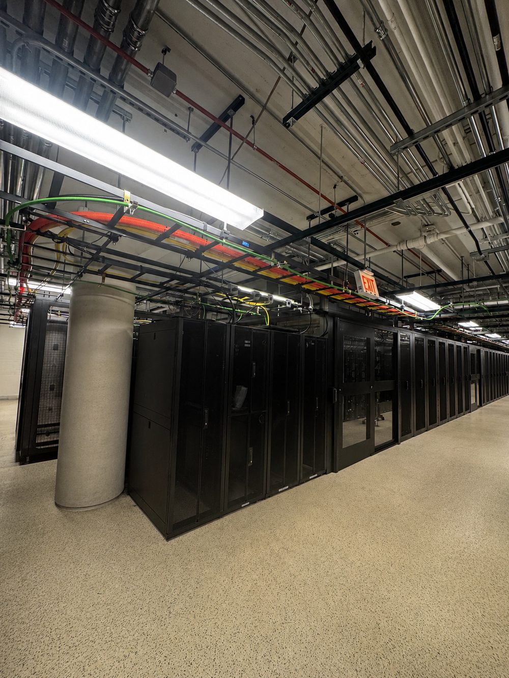 Data center server racks with overhead cable trays inside an enclosed facility